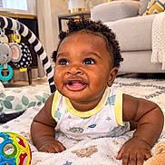 Prince joined the competition — help win amazing prizes! baby, child, infant, smiling, happy, portrait, curly_hair, indoor, living_room, blanket, toy, teddy_bear, playmat, couch, plant, home, sitting, tummy_time, colorful, family_photo