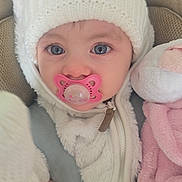 Elodie joined the competition — help win amazing prizes! baby, pacifier, hat, pom_poms, knitwear, plush_toy, soft_toy, mirror, child, blue_eyes, white_clothing, pink_blanket, car_seat, seatbelt, close_up, portrait, cute, infant, warm_clothing, indoor