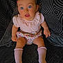 Elodie joined the competition — help win amazing prizes! baby, child, blue_eyes, pink_clothing, floral_shorts, socks, couch, cushion, patterned_fabric, curious_expression, indoors, seated, infant, cute, portrait, soft_lighting, small_hair_clip, legs, hands, comfortable