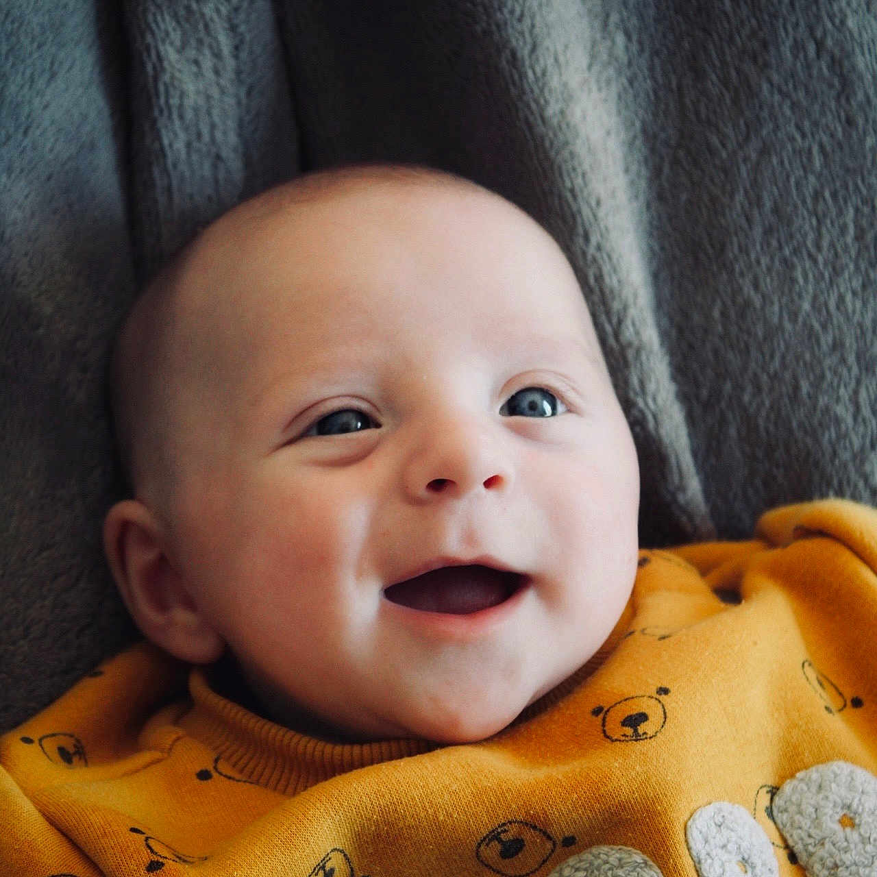 Lyam participe au concours pour gagner de l'argent avec cette photo : baby, bear_pattern, blanket, blue_eyes, casual, child, closeup, cozy, cute, face, happy, indoors, infant, person, portrait, smiling, soft_texture, sweater, warm, yellow_clothing