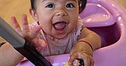 Aitana is registered to the contest to win money with this photo: baby, child, infant, smiling, happy, portrait, indoor, playroom, ride_on_toy, pink, toy_vehicle, sitting, reaching, hand, open_mouth, brown_hair, face, family, home, number_three
