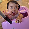 baby, child, infant, smiling, happy, portrait, indoor, playroom, ride_on_toy, pink, toy_vehicle, sitting, reaching, hand, open_mouth, brown_hair, face, family, home, number_three