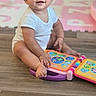 Aitana joined the competition — help win amazing prizes! baby, child, infant, smiling, sitting, indoor, playroom, toy, musical_toy, colorful, play_mat, wooden_floor, white_shirt, short_hair, portrait, happy, cute, face, baby_teeth, photography