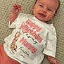 Esme is registered to the contest to win money with this photo: baby, infant, smiling, shirt, giraffe, balloons, text, carpet, lying_down, cute, child, portrait, happy, clothing, toddler, person, celebration, message, love, soft_lighting