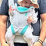 adult, baby, baby_carrier, bear_pattern, black_shirt, child, clothing, cute, face, frog_hat, hands, happy, hat, holding, infant, joy, outdoor, pajamas, person, smile