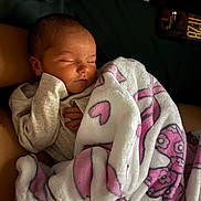 Cherish is registered to the contest to win money with this photo: newborn, baby, sleeping, infant, portrait, blanket, pink_blanket, cartoon_blanket, cozy, indoors, close_up, face, closed_eyes, peaceful, bundled, clothing, arm, adult, soft_lighting, nap