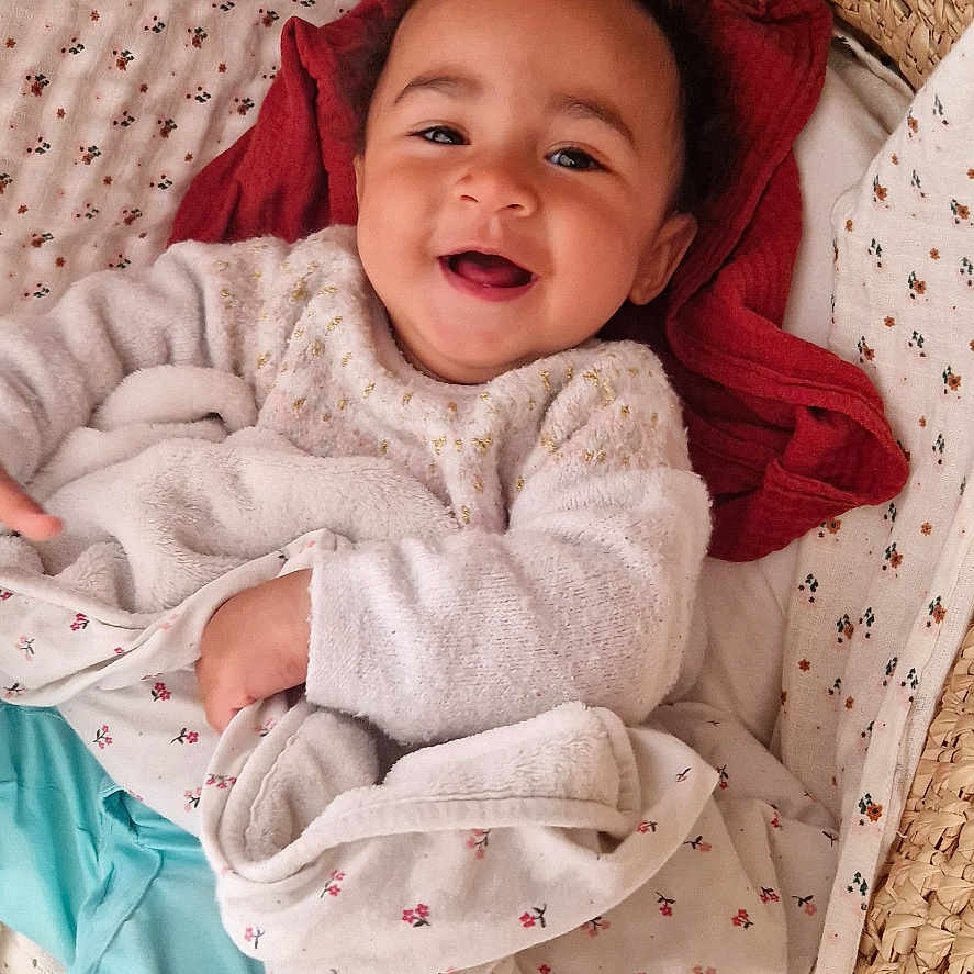 Lila participe au concours pour gagner de l'argent avec cette photo : baby, basket, bed, blanket, clothing, cradle, crib, cushion, face, furniture, happy, hat, head, hood, infantbed, newborn, person, photography, portrait, smile