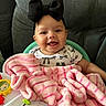baby, black_bow, blanket, pink_blanket, smiling, happy, infant, toy, chair, headband, cute, child, indoors, cozy, clothing, face, person, seated, plaything, soft