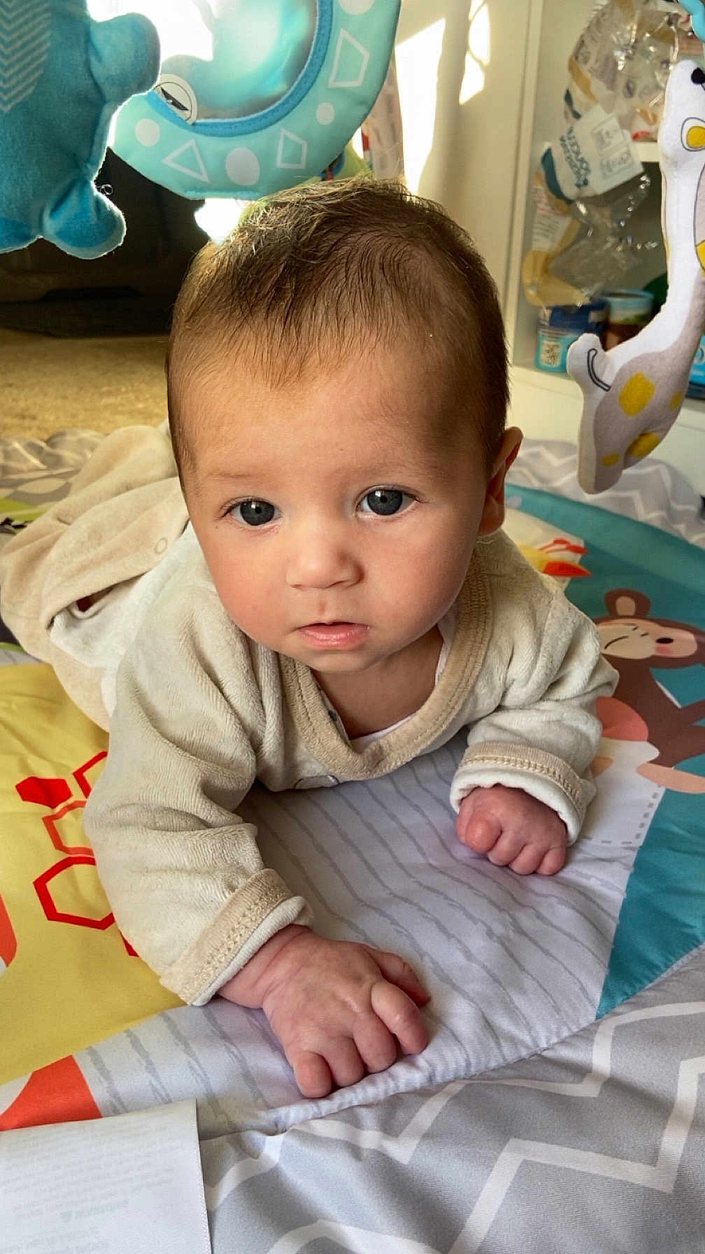 Thélio a rejoint le concours — aidez-le/la à gagner de superbes lots ! baby, infant, play_mat, soft_toys, curious, indoors, child, cute, face, hands, clothing, floor, colorful, expression, young, portrait, playtime, home, blanket, light