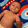 Mateo is registered to the contest to win money with this photo: baby, infant, diaper, smile, face, skin, arm, blanket, pattern, colorful, cute, child, lying_down, expression, indoors, human, young, playful, portrait, soft