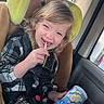 toddler, child, car_seat, car_interior, snack_container, lollipop, happy, smiling, plaid_shirt, seatbelt, window, hair, toy_car_seat, clothing, safety, child_seat, portrait, indoor, childhood, travel
