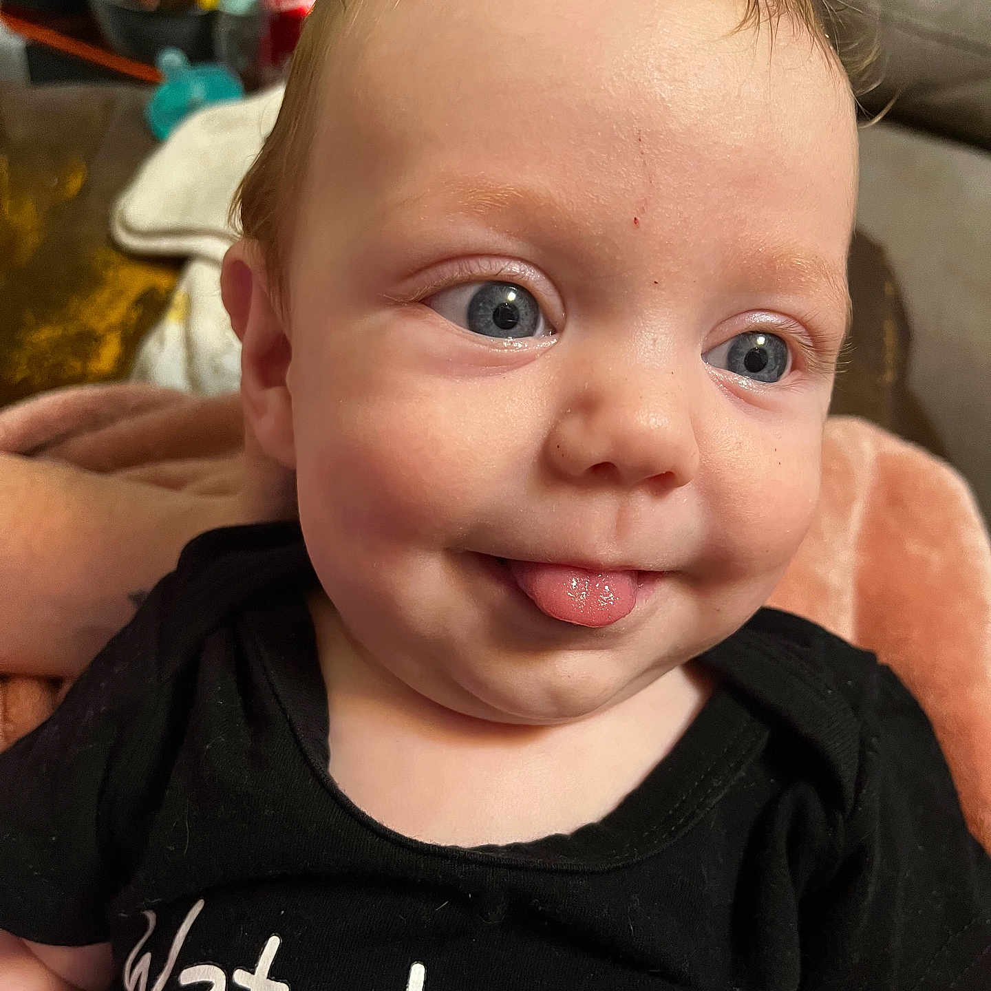 Henry joined the competition — help win amazing prizes! baby, child, face, blue_eyes, tongue_out, black_shirt, hair, indoor, blanket, cute, infant, person, smile, closeup, expression, skin, head, young_child, clothing, human