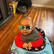 Aaron is registered to the contest to win money with this photo: baby, sunglasses, walker, red_clothing, mickey_mouse, toy, floor, wooden_floor, indoor, child, person, bib, headwear, accessory, furniture, bag, backpack, window, reflection, cozy_room