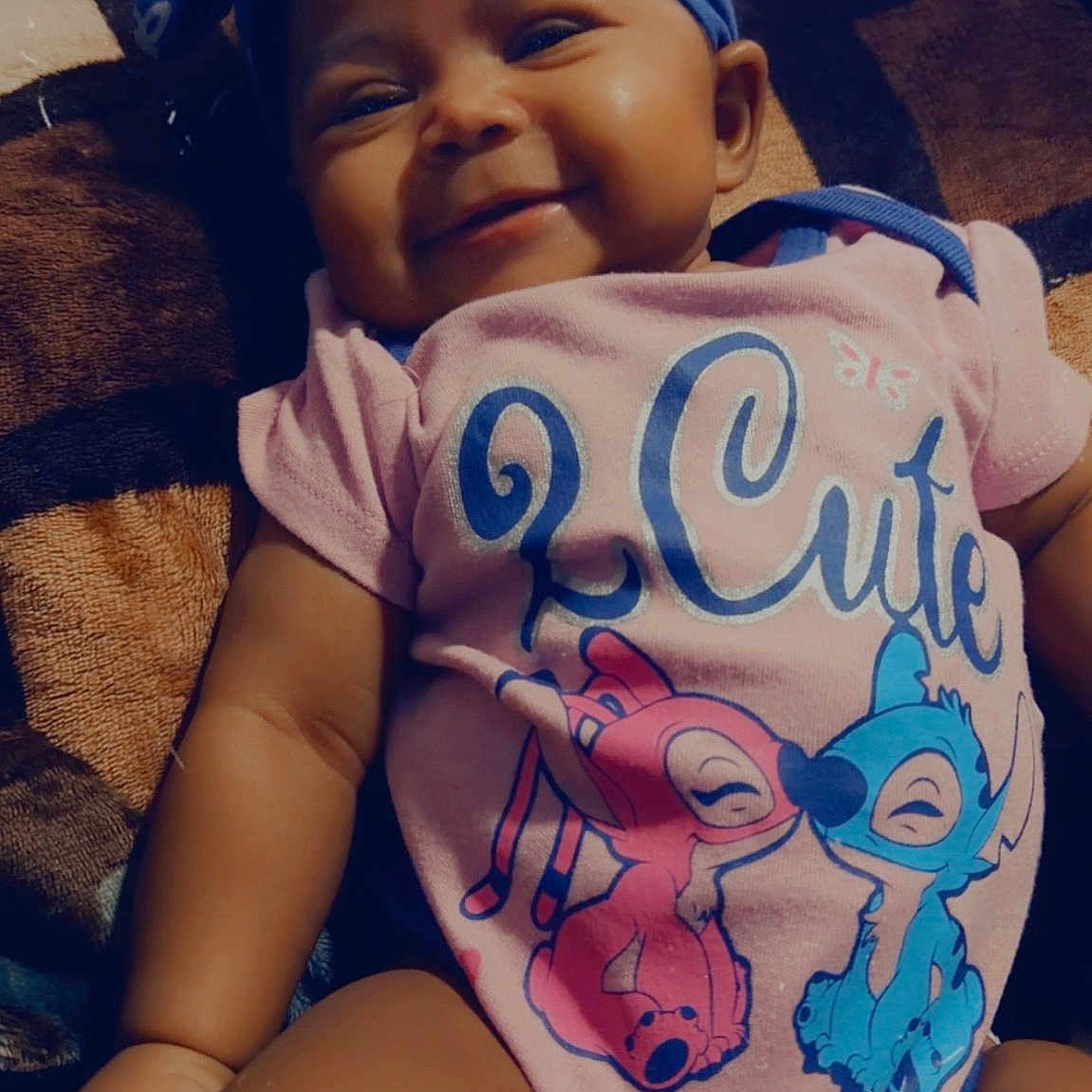 Icelynn Shawnta is registered to the contest to win money with this photo: arm, baby, blanket, cartoon_print, chubby_cheeks, cute, eyes, fabric, face, hand, headband, indoor, infant, legs, lips, onesie, pattern, portrait, sitting, smiling