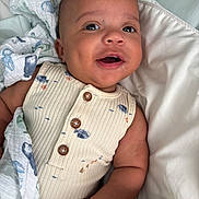 William joined the competition — help win amazing prizes! baby, infant, smiling, blanket, onesie, buttoned_clothing, bed, white_bed, lying_down, happy, cute, child, human, portrait, indoors, soft_texture, fabric, comfort, face, skin