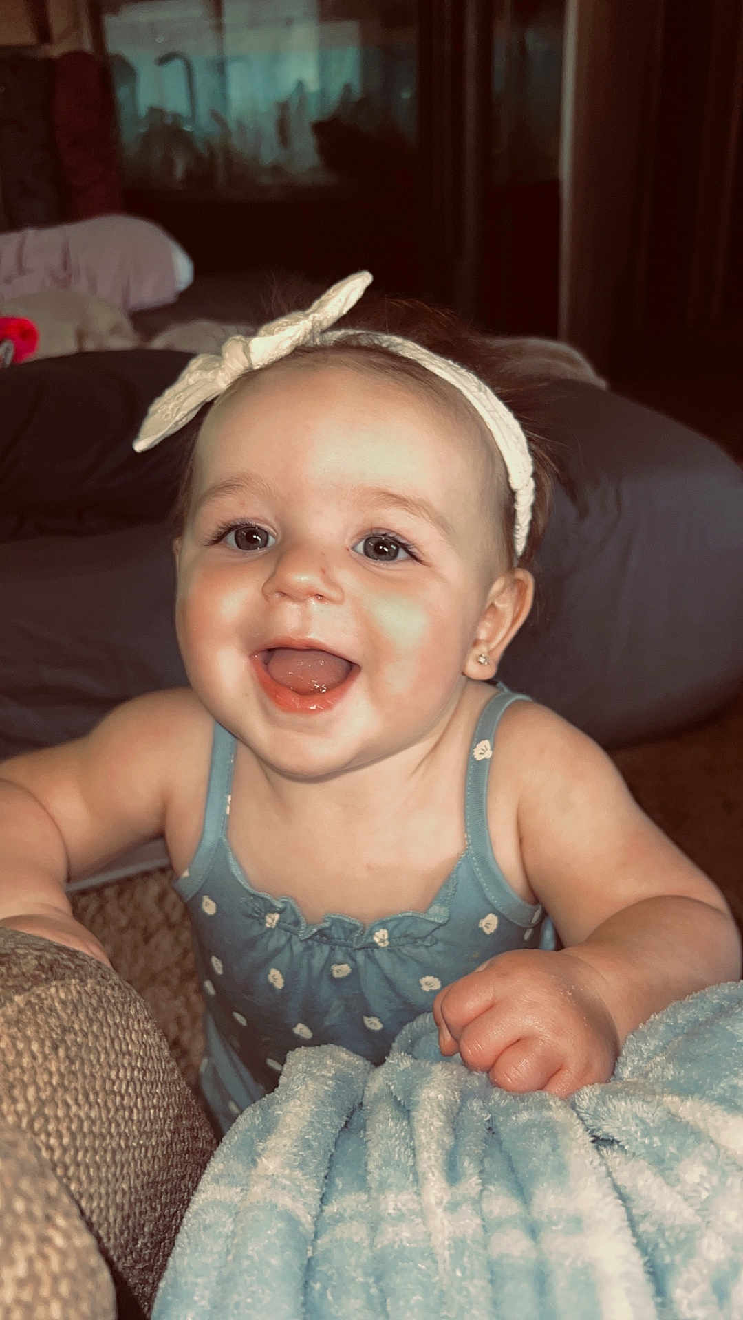 Kesley joined the competition — help win amazing prizes! baby, headband, blue_dress, blanket, smiling, indoor, furniture, happy, child, face, cute, person, infant, soft, cozy, skin, hand, expression, young, warm_lighting