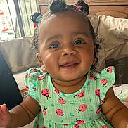Kalisa is registered to the contest to win money with this photo: toddler, child, baby, smile, happy, curly_hair, hair_buns, green_dress, ladybug_pattern, indoor, portrait, cute, infant, person, young_child, seated, natural_light, skin, face, apparel