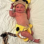 newborn, baby, infant, crocheted_clothing, giraffe_costume, hat, braided_tail, diaper, hospital_wristband, lying_down, white_sheet, cute, baby_girl, baby_boy, face, skin, hand, foot, expression, portrait