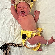 Autumn joined the competition — help win amazing prizes! newborn, baby, infant, crying, costume, hand_knitted, giraffe, yellow, black_spots, braided_tail, diaper, white_sheet, lying_down, cute, small_hands, hospital_bracelet, headgear, soft_texture, expression, baby_clothing