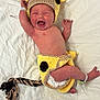 newborn, baby, infant, crying, costume, hand_knitted, giraffe, yellow, black_spots, braided_tail, diaper, white_sheet, lying_down, cute, small_hands, hospital_bracelet, headgear, soft_texture, expression, baby_clothing