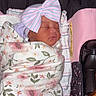 baby, baby_carrier, blanket, bow, child, cozy, cute, floral, headwear, indoors, infant, newborn, person, pink, portrait, resting, sleeping, soft, striped, wrapped