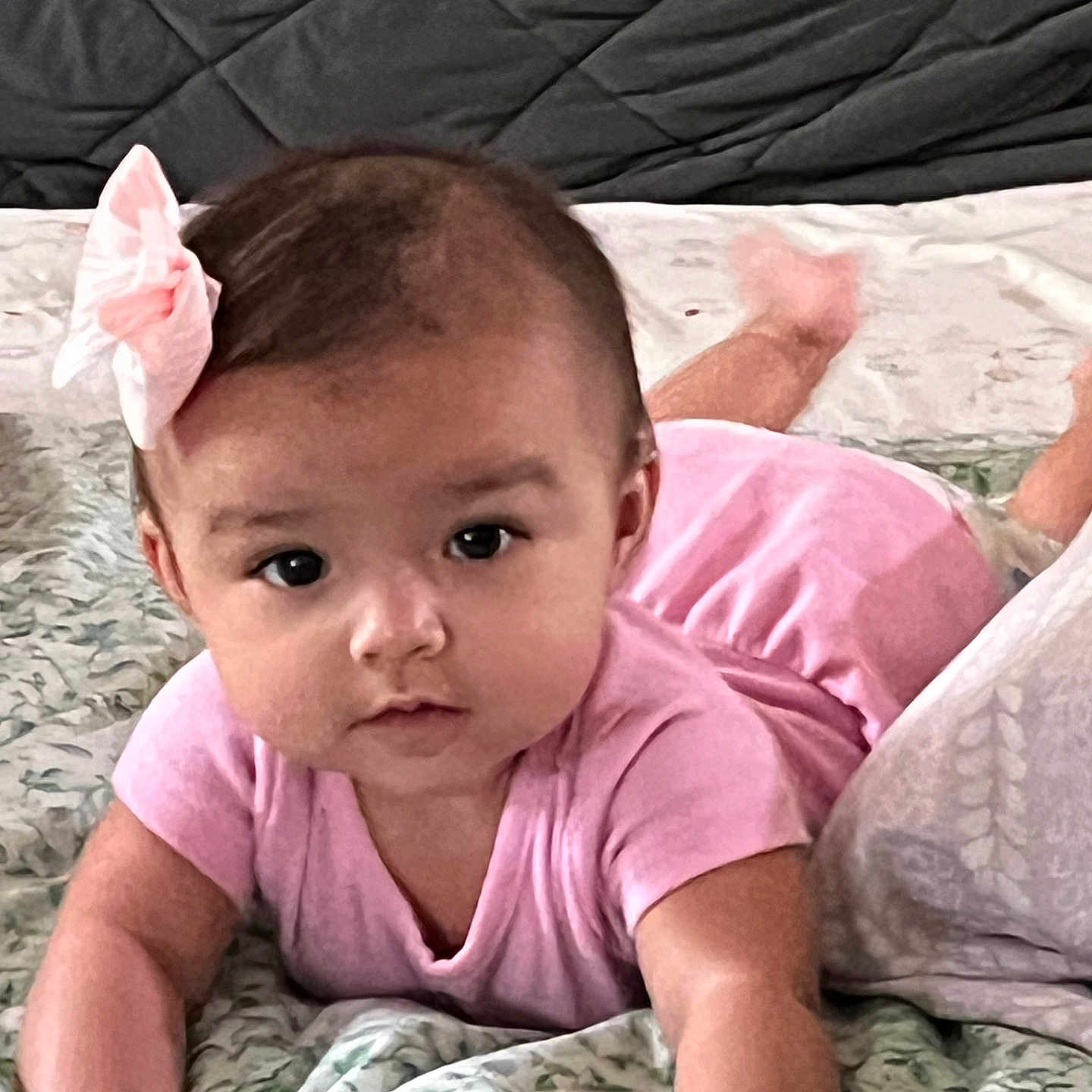 Celerina is registered to the contest to win money with this photo: arms, baby, bed, blanket, bow, child, cozy, cute, expression, eyes, face, head, indoor, infant, lying_down, pink_clothing, portrait, skin, soft_texture, young