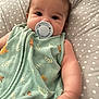 évy participe au concours pour gagner de l'argent avec cette photo : baby, pacifier, green_clothing, animal_print, polka_dot, cushion, infant, child, sleeping_sack, cute, portrait, closeup, soft_lighting, indoors, chubby_cheeks, hand, face, young_child, resting, cozy