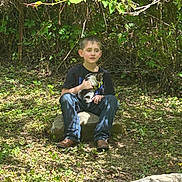 Jameson joined the competition — help win amazing prizes! child, boy, kitten, animal, pet, outdoor, nature, leafy, rock, sunlight, shadows, greenery, casual_clothing, jeans, tshirt, sitting, young, peaceful, daylight, forest_floor