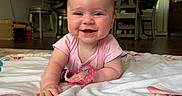 Lilith joined the competition — help win amazing prizes! baby, child, smiling, pink_clothing, blanket, indoor, dining_room, furniture, person_in_background, happy, face, head, eyes, skin, hand, floor, curtains, light, home, infant