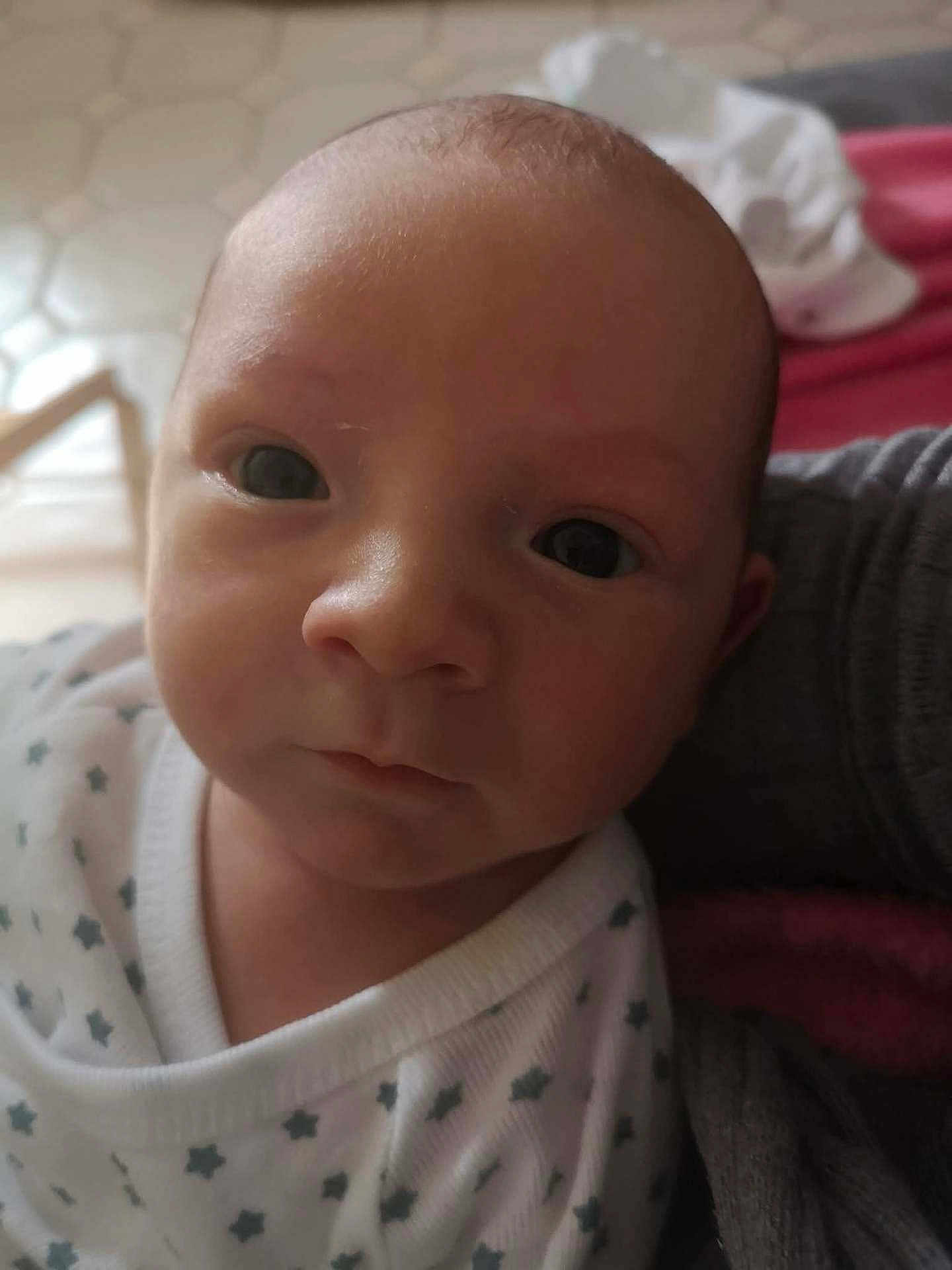 Fiurenzu a rejoint le concours — aidez-le/la à gagner de superbes lots ! baby, infant, face, eyes, close_up, portrait, newborn, clothing, star_pattern, white, skin, head, expression, looking, person, cute, indoors, soft_light, fabric, calm