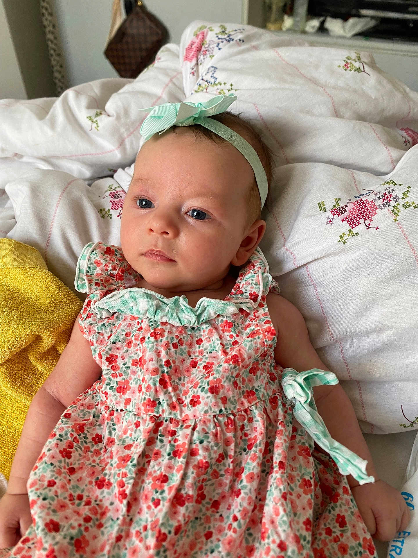 Esmé-Ivy is registered to the contest to win money with this photo: baby, infant, girl, floral_dress, headband, bow, bed, quilt, blanket, soft_lighting, indoors, peaceful, portrait, cute, child, young, sleepwear, hand, face, blue_eyes