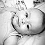 arm, baby, bedding, black_and_white, blanket, child, closeup, cute, expression, eyes, face, indoors, infant, lying_down, monochrome, plush_toy, portrait, sleepwear, soft_toy, young