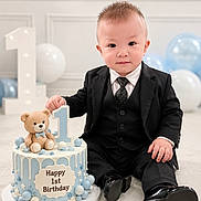 Danis joined the competition — help win amazing prizes! baby, child, toddler, birthday, cake, teddy_bear, suit, tie, black_clothing, portrait, sitting, smiling, balloons, number_one, indoor, celebration, party, decorations, photography, happy_birthday