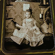 Aimelya is registered to the contest to win money with this photo: child, girl, vintage, sepia, dress, costume, portrait, old_fashioned, bench, wallpaper, decor, beads, feather, headband, props, sitting, smile, indoor, photo_frame, antique