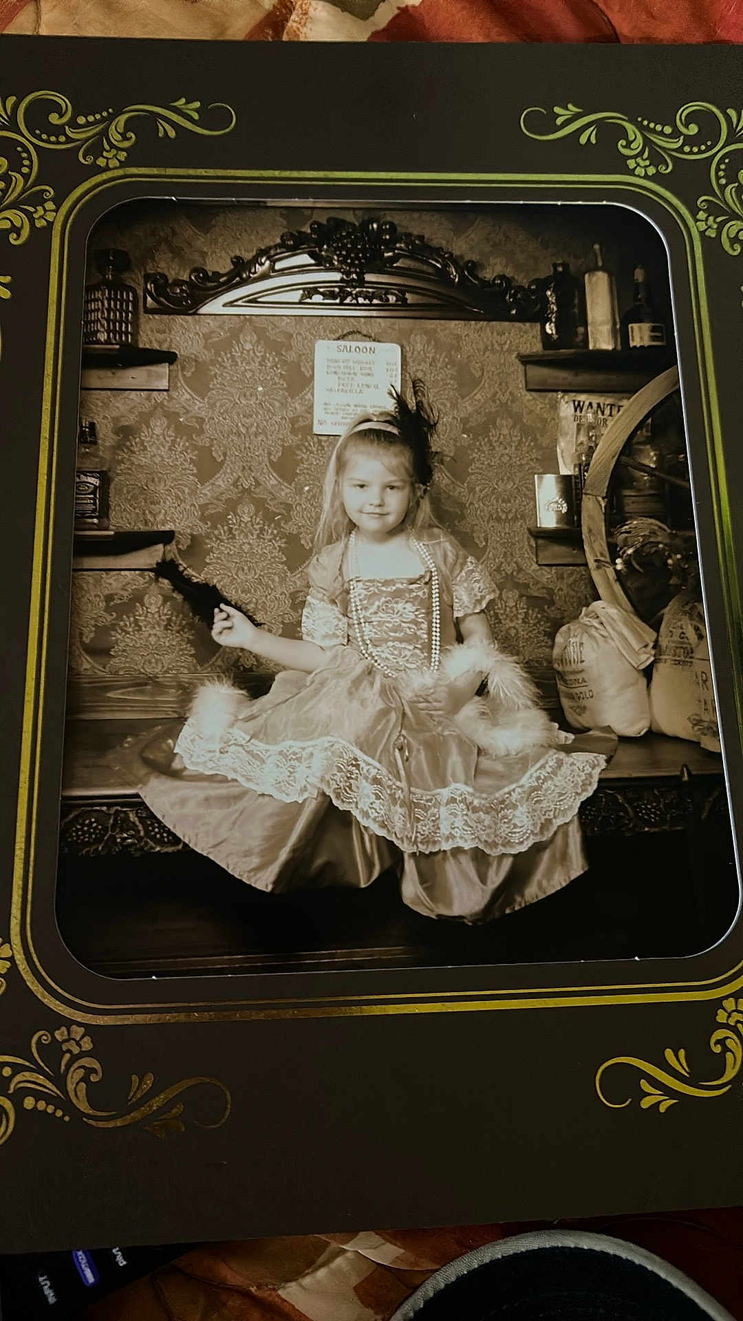Aimelya is registered to the contest to win money with this photo: child, girl, vintage, sepia, dress, costume, portrait, old_fashioned, bench, wallpaper, decor, beads, feather, headband, props, sitting, smile, indoor, photo_frame, antique