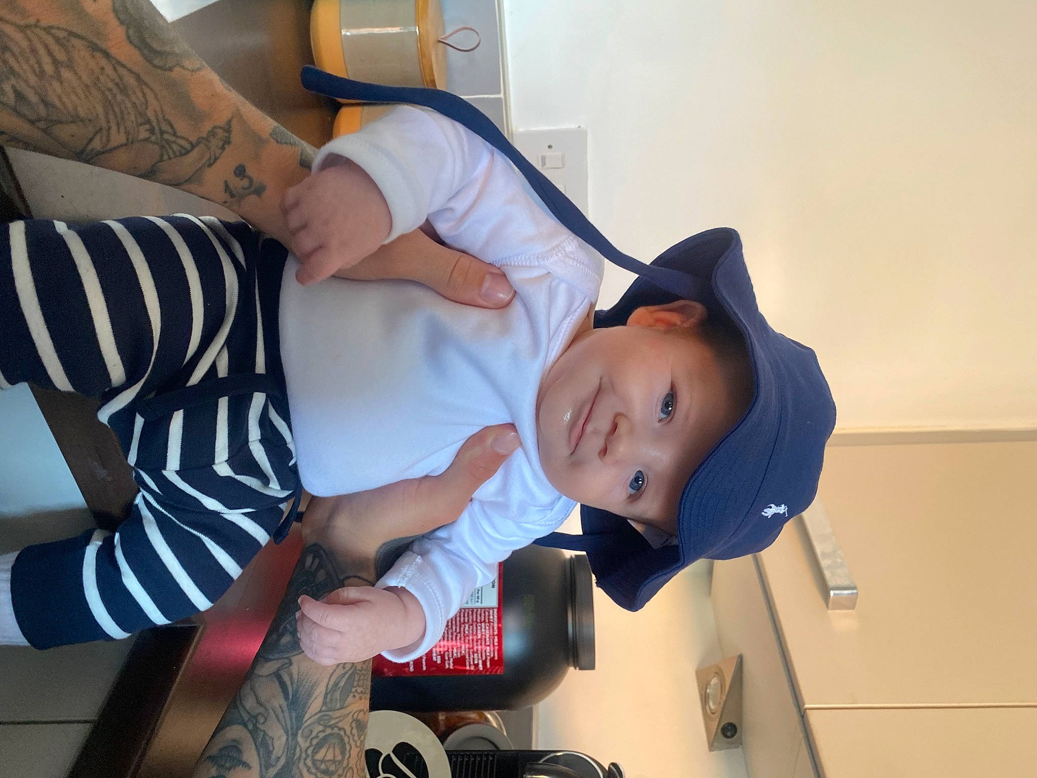 Axel joined the competition — help win amazing prizes! arm, baby, baby_toddler_clothing, baseball_cap, cap, comfort, elbow, finger, fun, gesture, happy, hat, headwear, human_leg, joy, knee, person, room, sitting, t_shirt