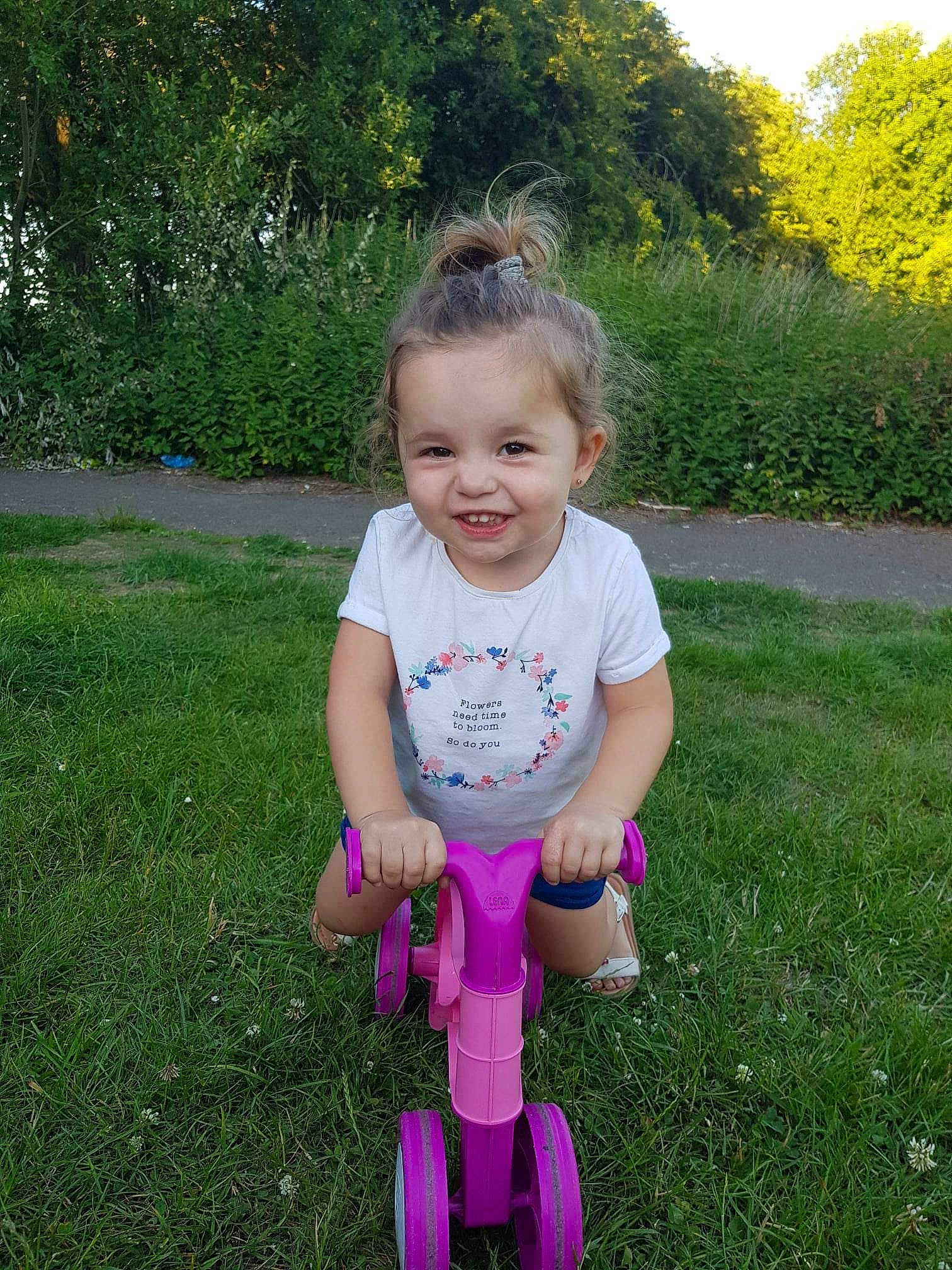 Alessia participe au concours pour gagner de l'argent avec cette photo : baby_toddler_clothing, child, fun, garden, grass, grassland, happy, joy, lawn, leisure, magenta, people_in_nature, person, pink, plant, recreation, sitting, smile, summer, toddler