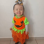 Lea a rejoint le concours — aidez-le/la à gagner de superbes lots ! black_socks, child, cute, festive, green_accents, halloween_costume, happy, headband, holiday, indoor, long_sleeves, orange_dress, portrait, pumpkin, smiling, spider_decoration, standing, tile_floor, toddler, witch_hat