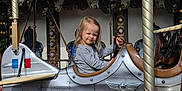 Lea a rejoint le concours — aidez-le/la à gagner de superbes lots ! airplane_ride, amusement_park, carousel, child, daylight, decorative, entertainment, family, fun, leisure, metal, outdoor, person, playful, ride, seat, smile, steering_wheel, toy, vintage