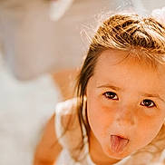 Louna participe au concours pour gagner de l'argent avec cette photo : blurry_background, brown_eyes, child, childhood, closeup, cute, expression, face, freckles, fun, girl, hair_accessory, happy, indoors, playful, portrait, smiling, soft_light, tongue_out, young