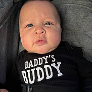 Ayce joined the competition — help win amazing prizes! baby, black_outfit, cheeks, child, closeup, clothing, curious_expression, cute, eyes, fabric_background, face, hand, indoors, infant, newborn, person, portrait, skin, text_on_clothing, young_child