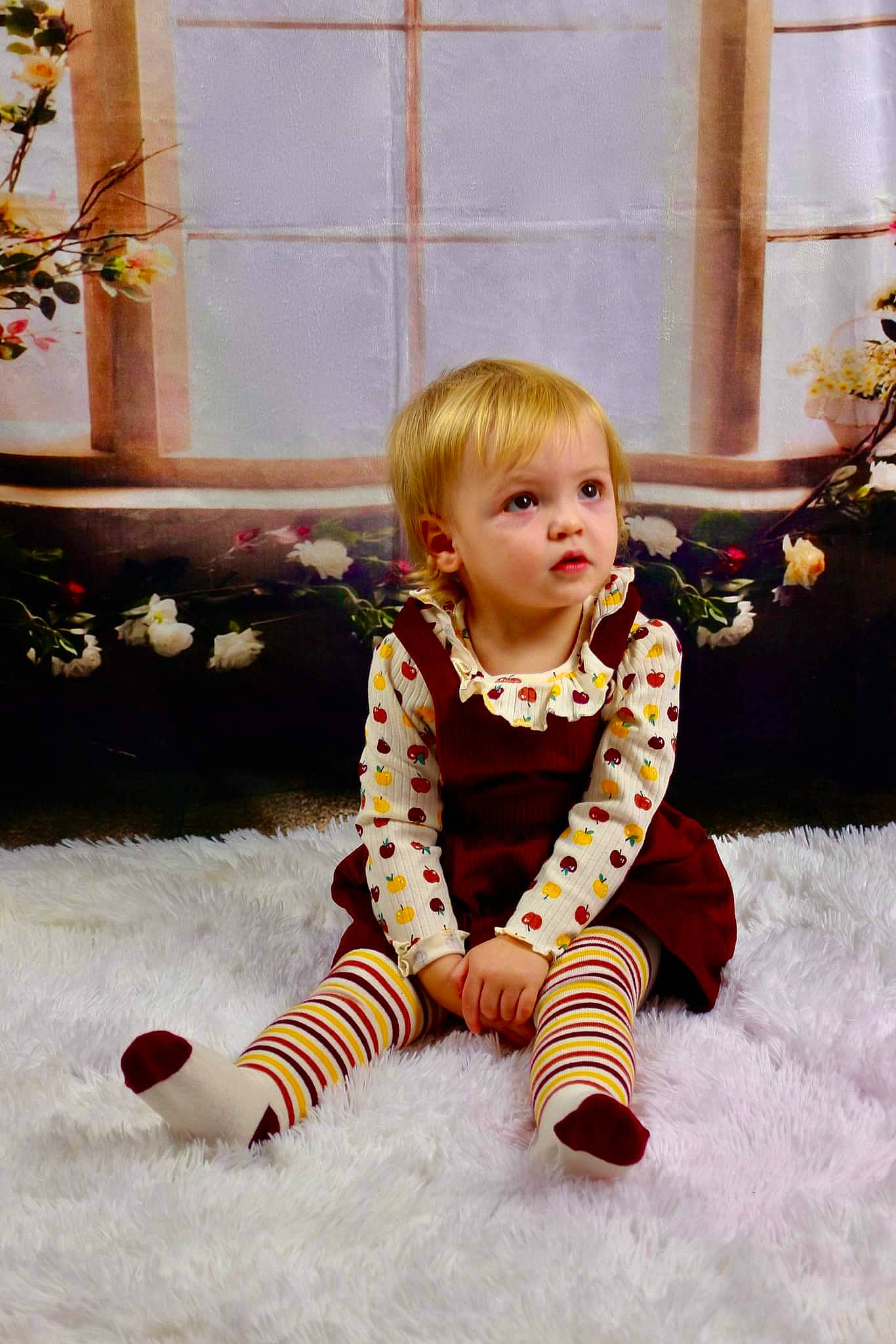 Adeline is registered to the contest to win money with this photo: baby, baby_toddler_clothing, child, flooring, flowerpot, fun, fur, grass, happy, human_leg, pattern, person, plant, portrait_photography, sitting, sleeve, smile, toddler, window, winter