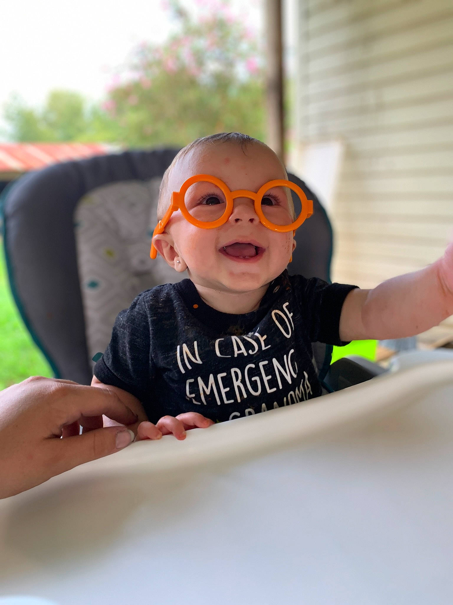 Xander is registered to the contest to win money with this photo: baby_toddler_clothing, chair, child, eyewear, fun, glasses, goggles, happy, leisure, person, personal_protective_equipment, recreation, room, sitting, sleeve, smile, sunglasses, t_shirt, toddler, vacation