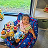 baby, child, infant, sitting, activity_chair, plush_toy, stuffed_animal, toy, indoor, window, grass, sunlight, portrait, face, wide_eyes, pink_clothing, colorful, playroom, floor, smiling_toy