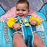 baby, child, smiling, float, safety_harness, yellow_clothing, blue_float, indoor, infant, cute, chubby_cheeks, playful, water_toy, baby_float, seat, happy, portrait, closeup, head, body