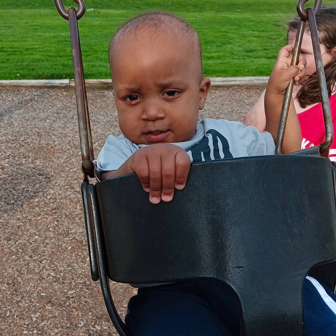 Ky'Ree is registered to the contest to win money with this photo: baby, baby_products, baby_toddler_clothing, child, city, fun, grass, leisure, outdoor_furniture, outdoor_play_equipment, person, plant, play, product, public_space, recreation, sitting, swing, toddler, vacation