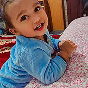 Arsalan joined the competition — help win amazing prizes! toddler, child, blue_fleece, smiling, indoor, bedspread, floral_pattern, furniture, home, happy, face, person, hands, couch, carpet, wall, cabinet, toy, television, cute