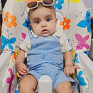 Azlaan joined the competition — help win amazing prizes! baby, child, infant, high_chair, blue_overalls, socks, sunglasses, face, expression, indoor, balloons, lights, colorful, pattern, floral, butterfly, cute, seated, person, portrait