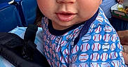 Billy is registered to the contest to win money with this photo: baby, baseball_pattern, blue_shirt, casual, child, close_up, clothing, curious, daylight, event, face, hand, infant, outdoor, people, person, portrait, seats, sitting, stadium