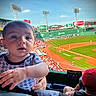 baby, child, baseball, stadium, sports, crowd, daylight, outdoor, field, green, grass, people, hat, spectator, game, scoreboard, lights, person, clothing, seating